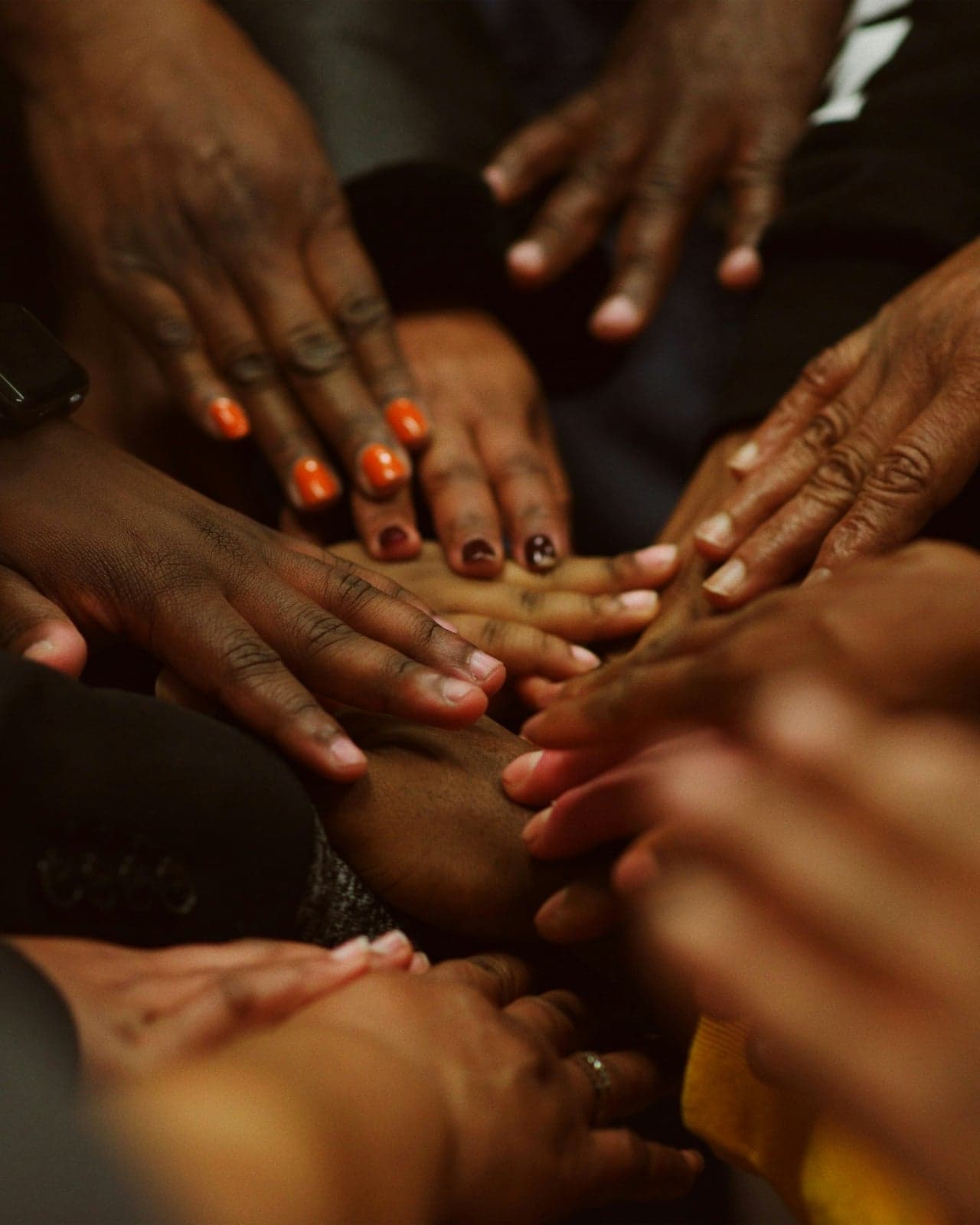 Mãos de várias pessoas sobrepostas em luz dourada — gesto de aliança coletiva multiétnica, sem rostos identificáveis